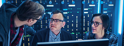 De jeunes employés de l'informatique montrent à leur chef dans la salle des serveurs comment optimiser la sécurité du réseau