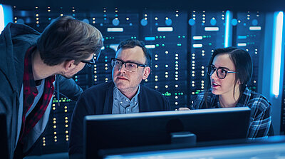 De jeunes employés de l'informatique montrent à leur chef dans la salle des serveurs comment optimiser la sécurité du réseau