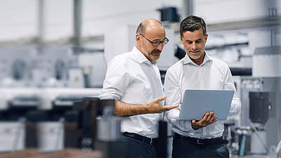 Deux hommes regardent un ordinateur portable et discutent