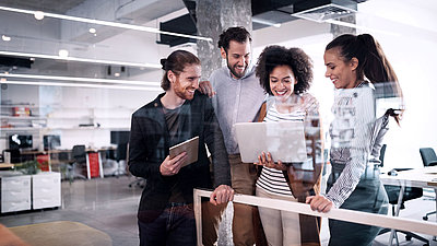 Groupe de jeunes employés de bureau regardant ensemble un ordinateur portable dans un bureau moderne