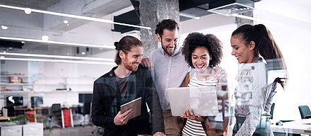 Groupe de jeunes employés de bureau regardant ensemble un ordinateur portable dans un bureau moderne