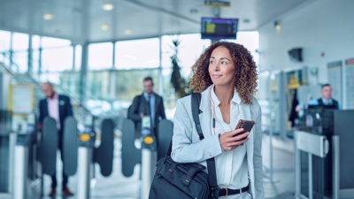 Une femme avec un téléphone portable à la main regarde vers la gauche dans un aéroport 