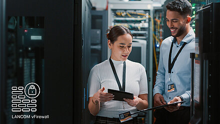 LANCOM vFirewall Deux collaborateurs se tiennent dans une salle de serveurs et discutent.