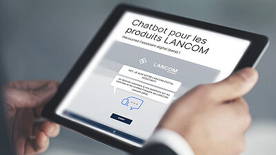Tablette avec vue de la page web de l'assistant digital de LANCOM, tenue à deux mains