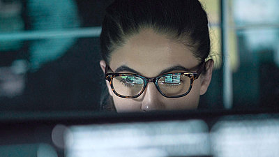 Une jeune femme à queue de cheval et lunettes contrôle le trafic de données sur un PC avec le moteur Deep Packet Inspection (DPI) R&S®PACE 2